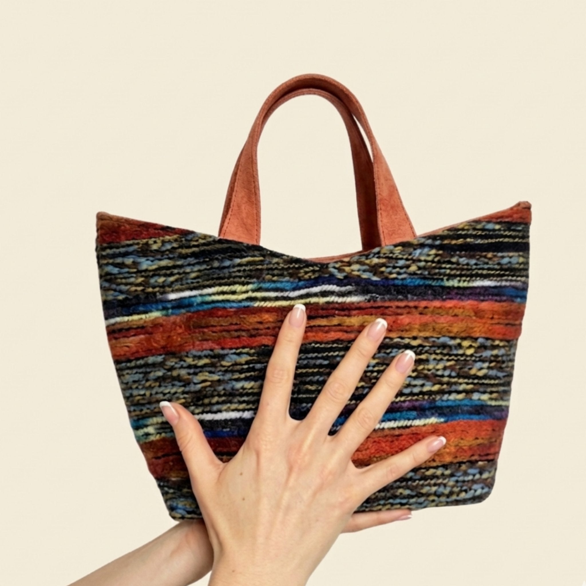 Hand hält handgemachte Wolltasche aus Wien – strukturierter Vienna Loom Tote mit buntem Gewebe


