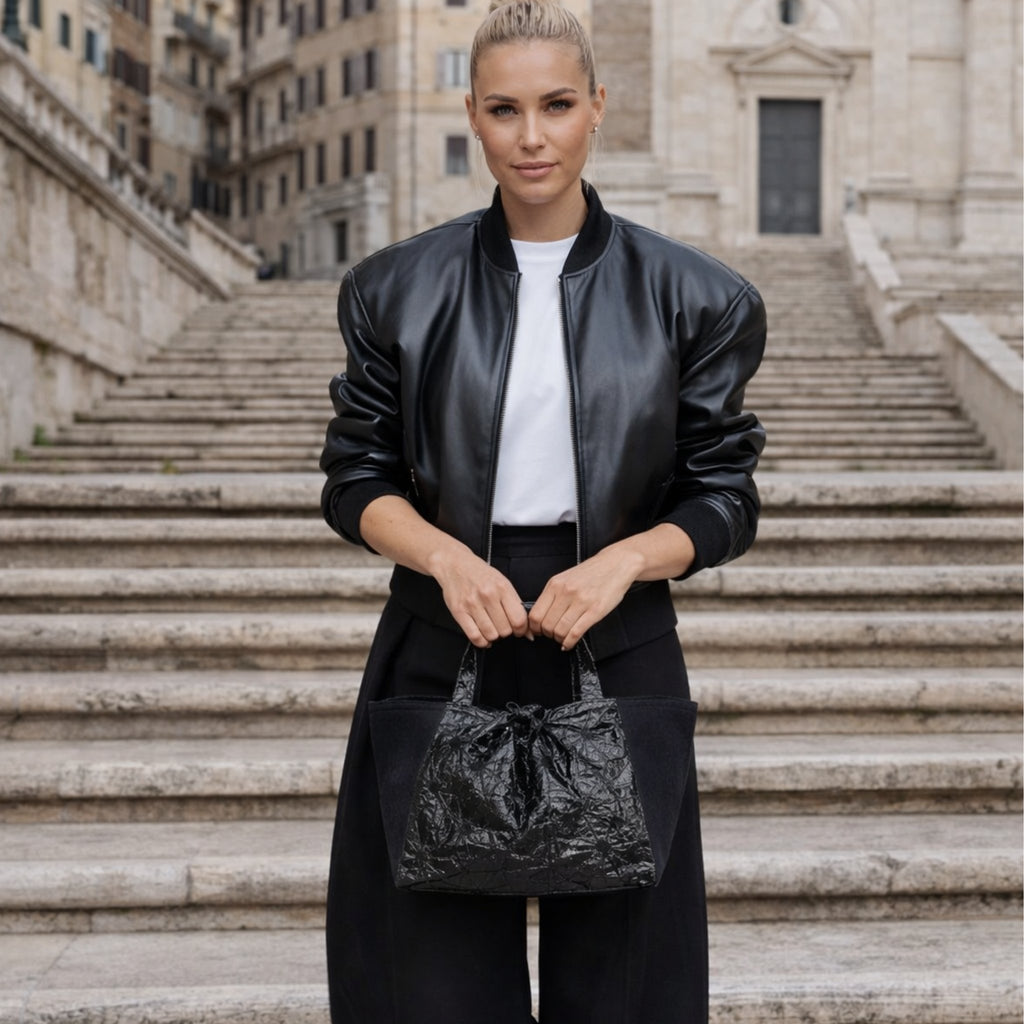 Schwarze Infinity Tote getragen von Model in urbaner Umgebung – handgemachte Tasche aus Wien

